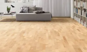 Suelo de parquet en color madera arce, con un sofá gris y estanterías llenas de libros al fondo.