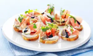 En tallrik med läckra crostini med lufttorkad skinka, färska fikon, krämig ost och ruccola, ringlad med balsamvinäger.