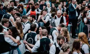 Menschen in Tracht tanzen ausgelassen. Ein Mann spielt Trompete. Hier ist heute Kirchweih in Franken!