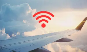 Widok z okna samolotu na chmury i skrzydło. Czerwony symbol Wi-Fi sugeruje, czy w samolocie jest wifi.