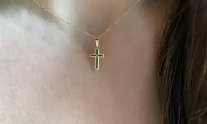 Una delicada cadena de oro sostiene una cruz de oro pequeña, un símbolo de fe y elegancia.