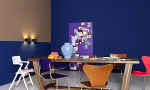 Zweifarbig gestrichene Wand in Blau und Beige mit einem Holztisch, bunten Stühlen und einer Pinnwand. Tolle wand zweifarbig streichen ideen!