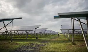 Un campo de paneles solares bajo un cielo nublado. A pesar de la falta de sol directo, las placas solares cargan energía, demostrando su eficiencia.
