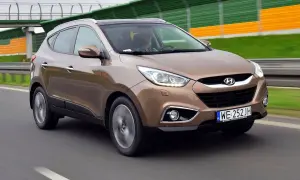 Brązowy Hyundai ix35 w ruchu drogowym, z widocznym kierowcą.