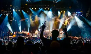 Capturing the energy of a live show is key to how to become a concert photographer. This image shows a band performing under dramatic stage lights to an enthusiastic crowd.