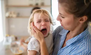Niña rubia llorando desconsoladamente mientras una mujer la consuela.