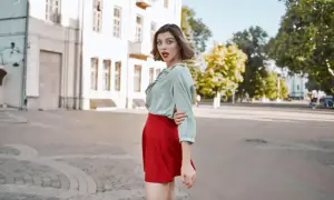 Kobieta w miętowej bluzce i czerwonej spódnicy, zastanawia się, jaka bluzka do czerwonej spódnicy pasuje najlepiej.