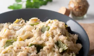 Un crémeux risotto poireaux, parsemé de grains de moutarde, servi dans un bol gris.