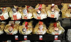 Księża w złotych szatach, z czerwonymi zdobieniami, siedzą w ławkach, czytając księgi. Ich skupienie przypominało dawnych pogan podczas rytuałów.