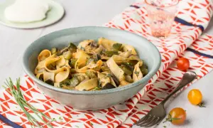 Un plat de pâtes one pot aux légumes d'été, courgettes, aubergines et champignons, garni d'herbes fraîches.