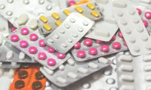 Stos leków w blistrach, w tym różowe i żółte tabletki, które mogą być stosowane jako leki na demencję.