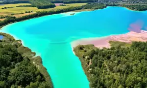 Turkusowe jezioro w Koninie, otoczone zielenią i piaszczystymi brzegami, tworzy surrealistyczny krajobraz.