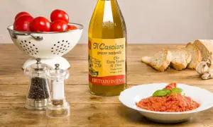 Un plat de pappa al pomodoro, garni de basilic, avec des tomates fraîches, du pain, de l'huile d'olive et des moulins à poivre et sel.