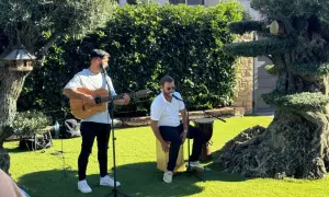 Dos músicos animan el jardín con rumbas para bailar. Uno toca la guitarra y canta, el otro canta y percute un cajón.