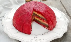 Zuppa inglese, un dessert a cupola con strati di crema e pan di Spagna, ricoperto da una glassa rossa vibrante.