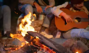 Przy ognisku rozbrzmiewają znane piosenki. Ktoś gra na gitarze, a wokół gromadzą się przyjaciele, ciesząc się wspólnym wieczorem.