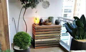 Mueble de madera para tapar unidad exterior aerotermia, decorado con plantas y objetos.