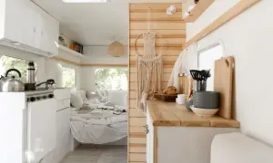 L'habitacle du camion aménagé offre une cuisine fonctionnelle et un coin couchage douillet, décoré d'une macramé murale.