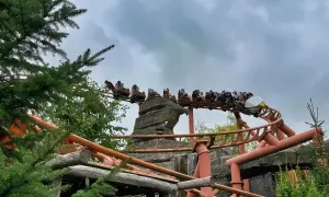 Kolejka górska w Legolandzie Niemcy z pasażerami pędzi po torach wśród skał i zieleni.