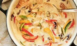 En krämig kycklinggryta med ris, full av färgglada paprikor och champinjoner i en smakrik sås.