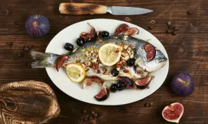 Un filet de dorade rôti, garni de figues, olives et citrons, prêt à être dégusté.