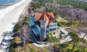 Elegancki budynek z czerwoną dachem i wieżą, blisko piaszczystej plaży i morza.