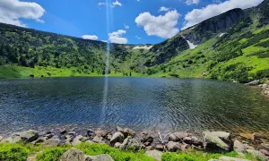 Piękne jezioro w górach, idealne na karpacz trasa. Zielone zbocza, skaliste brzegi i błękitne niebo.