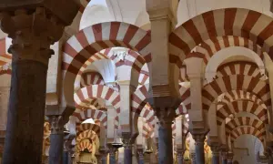 Columnas y arcos de herradura bicolores en la Mezquita de Córdoba, un ejemplo de sus diversos estilos arquitectónicos.
