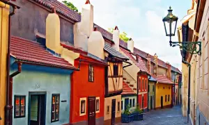 Kolorowa, wąska uliczka w Pradze, znana jako Złota Uliczka, z malowniczymi, ciasno zabudowanymi domkami i zabytkową latarnią.