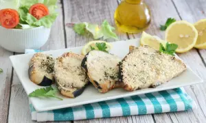 Fette di pesce spada in friggitrice ad aria, impanate con semi di sesamo e erbe aromatiche, servite con limone e insalata.