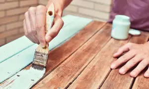 Persona aplica barniz a madera ya barnizada, renovando su aspecto.