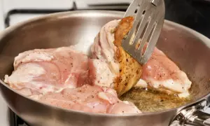 Smażony kurczak na patelni, obracany łopatką.