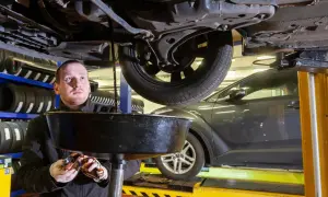 Mechanik zlewający zużyty olej z silnika diesla do miski.