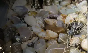 Gładkie kamienie, jak rodolit, w odcieniach beżu, szarości i bieli, ozdobione delikatnymi, złotymi liśćmi i gwiazdkami.