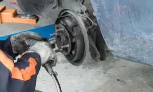Mécanicien travaillant sur un tambour de frein usé. L'outil pneumatique est utilisé pour retirer les boulons de la roue.