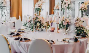 Eleganckie dekoracje potraw weselnych: pastelowe kwiaty, złote świeczniki i ciemne serwetki tworzą romantyczną atmosferę.