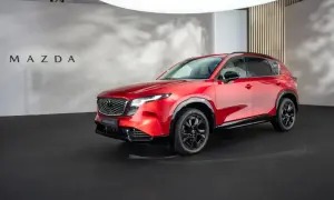 Lśniąca, czerwona Mazda CX-5 2026 prezentuje się na czarnej scenie.