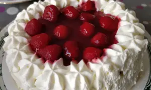 Pyszny tort z bitą śmietaną i truskawkami w galaretce. Zastanawiasz się, ile żelatyny do bitej śmietany? Ten deser wygląda idealnie!