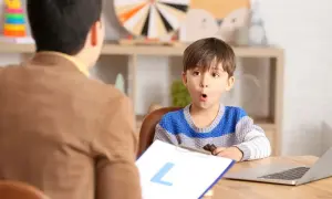 Un niño sorprendido interactúa con un logopeda que es un profesional de la comunicación.