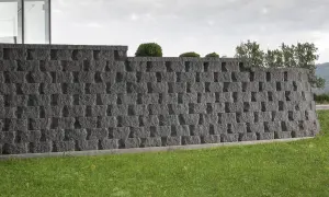 Nowoczesny pomysł na murek oporowy z szarego kamienia, idealny do ogrodu.