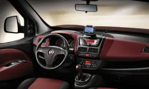 Interni Fiat Doblò con cruscotto rosso bordeaux, volante multifunzione, navigatore e radio.