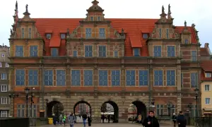 Wspaniała fasada Zielonej Bramy w Gdańsku, z ludźmi spacerującymi po brukowanym placu.
