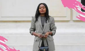 Frau in schickem Business-Outfit mit kariertem Blazer und schwarzer Handtasche, bereit für ein wichtiges Meeting.