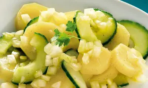 Ein appetitlicher Kartoffelsalat mit Gurken, verfeinert mit Zwiebeln und Petersilie.