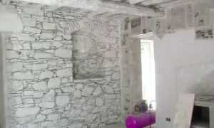 Interno con muro in pietra e intonaco grezzo, travi a vista e un compressore rosa.