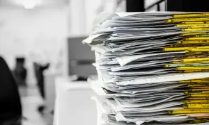 Stos papierów w żółtych segregatorach. Czas na porządki, co to znaczy? Niezwłocznie!
