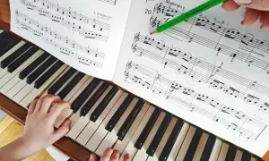 Dziecko uczy się grać na fortepianie, a zielony ołówek zaznacza nuty. Kto uczył Chopina grać na fortepianie? Może tak jak to dziecko, miał cierpliwego nauczyciela.