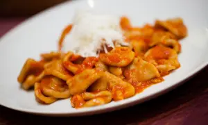 Orecchiette pugliesi con sugo rosso e una spolverata di formaggio grattugiato, un piatto che sa di casa e tradizione.