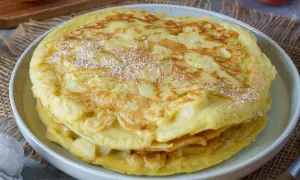 Ein gestapelter Apfelpfannkuchen, bestäubt mit Puderzucker. Das perfekte Apfelpfannkuchen Rezept für jeden Anlass.