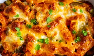 Un invitante pasta al forno ricetta della nonna, dorata e filante, con olive e prezzemolo fresco.